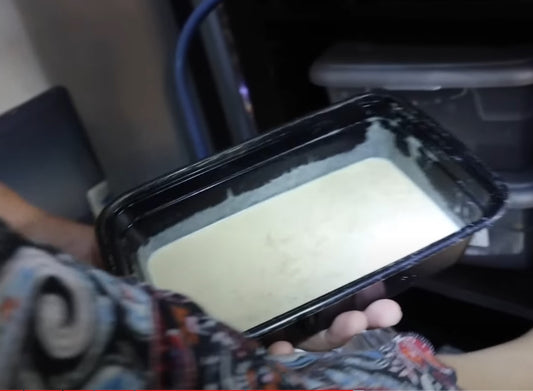 Cassie from Cassie's Critters & Creations holds a Banana Worm culture, showing a load of banana worms climbing the walls of the culture, ready for harvesting