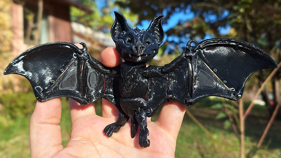 Articulated black fruit bat figurine, hand-held, showcasing intricate wing design, perfect for collectors and gothic decor enthusiasts.
