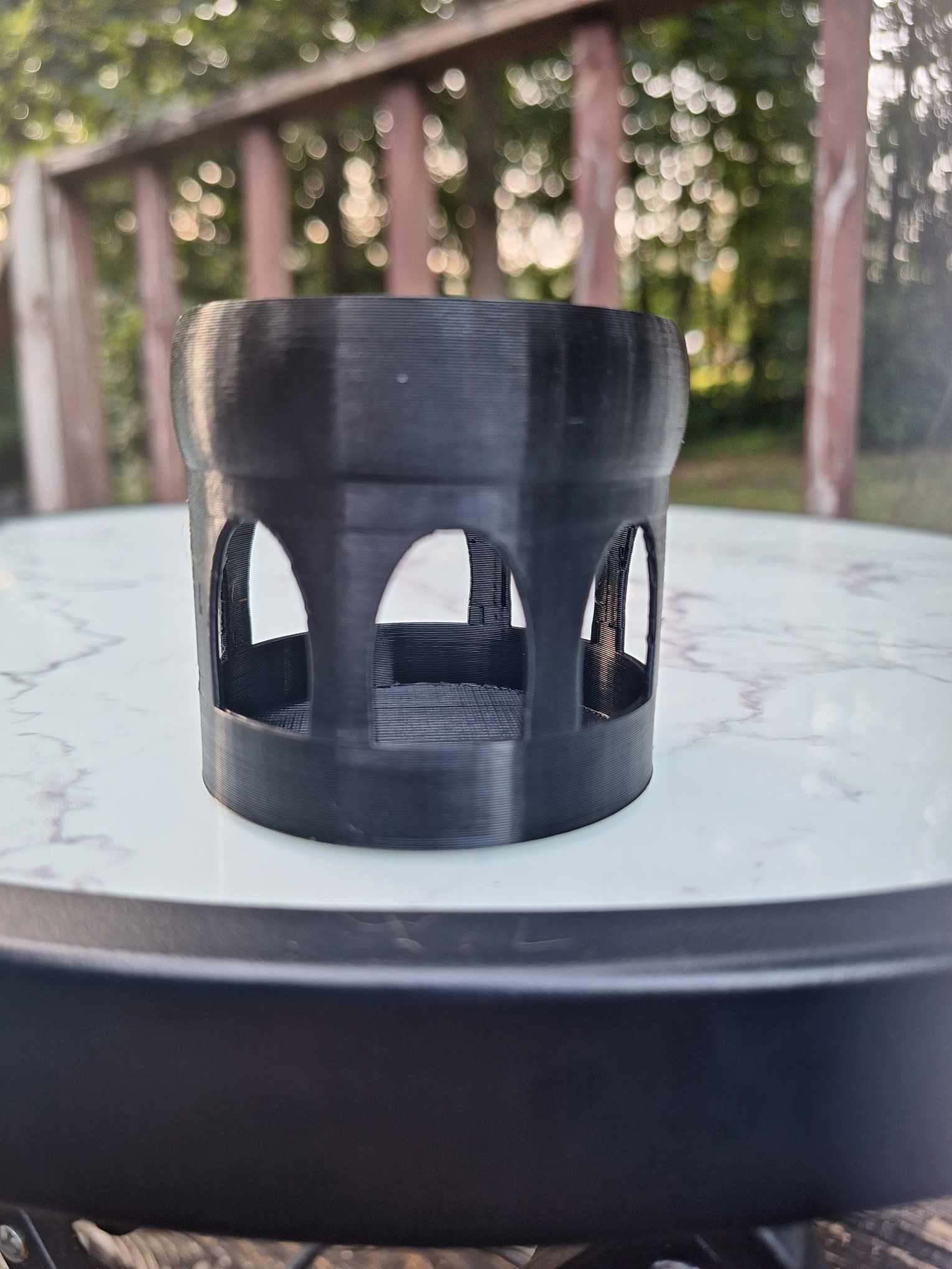 Elegant black Overture PETG 3D-printed Floating Shrimp Gazebo Feeder, designed to enhance feeding time in aquariums, displayed on a marble surface with a blurred natural background.
