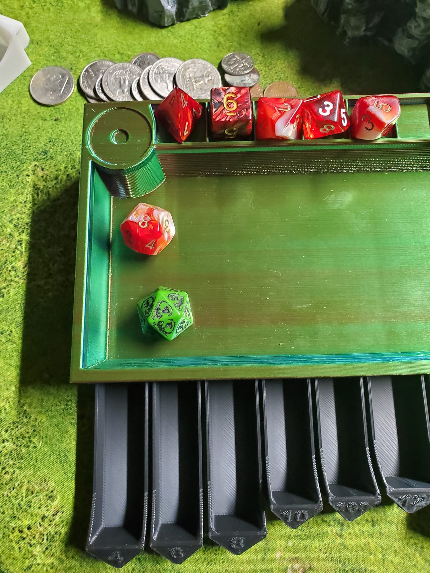 Custom red, blue, green, dice tray with black retractable drawers, each holding a set of vibrant red gaming dice, designed for Dungeons and Dragons and other tabletop games, displayed on a textured green surface.