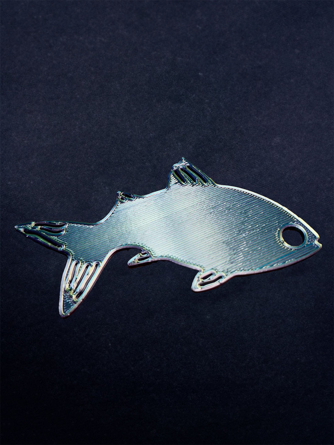 Silvery fish-shaped 'Fishy Bite' keychain with a shiny finish on a dark backdrop, ideal for nautical enthusiasts.