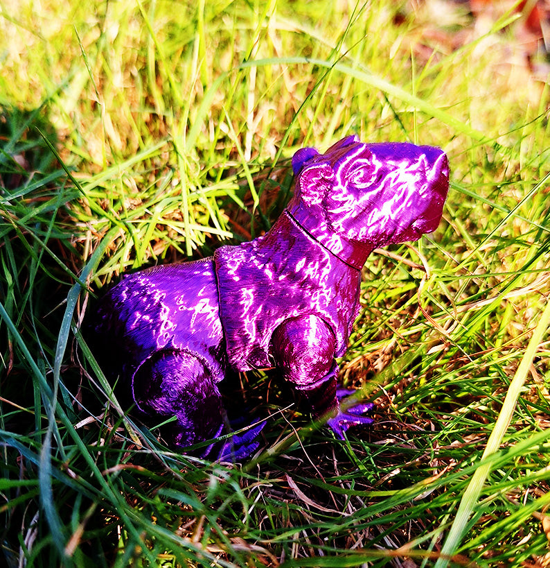 An articulated capybara figure is nestled in a patch of grass, printed in a lustrous Creality Purple Silk PLA. The segmented design allows for movement, catching light to reveal the silk filament's shimmering effect. This figure provides a tactile experience, enhancing outdoor discovery with a touch of whimsy and playful interaction.