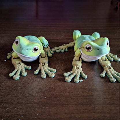 Two articulated White's tree frog models are positioned side by side on a wooden surface, each with a charming expression and wearing a small, white mask. Their subtle green shading and relaxed postures capture the whimsical nature of these popular amphibians, designed not only for visual appeal but also for tactile interaction.