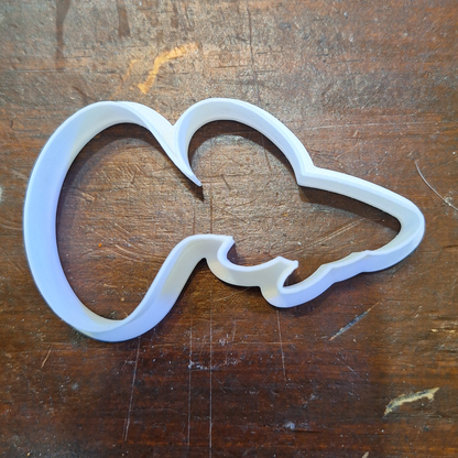 Fancy tail guppy-shaped cookie/clay cutter in Creality White PLA, designed with a curved tail detail, on a rustic wood background