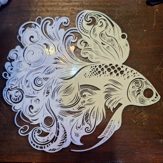 Elegant 3D-printed white guppy fish wall art with a tribal design, crafted from Creality White PLA, showcased against a dark wood background.