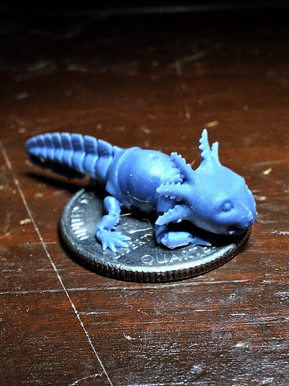 A tiny 3D-printed model of an Articulated Axolotl in ABS-like resin, perched atop a quarter to demonstrate its miniature size, from the 'Tinies' line by Cassie's Critters and Creations. Model design by MatMireMakes.
