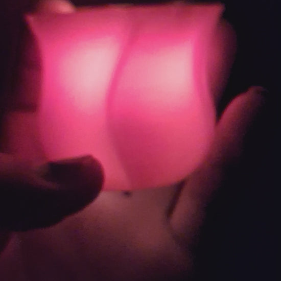 Video of a red 3D-printed rose with a flickering electronic tealight in the dark, highlighting the realistic flame effect, ending as the light is turned off and the scene fades to black.